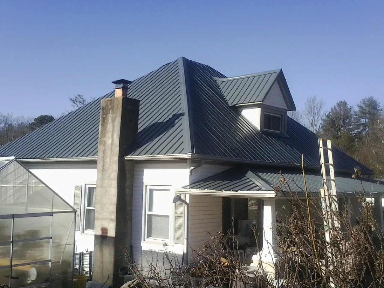 Dark blue standing seam metal roof on a white farmhouse with dormer — Slate & Tile Roof Repair by Roofing Brothers in Twin Valley