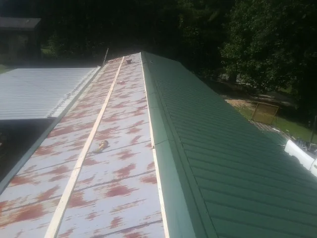 Old rusted panels beside newly installed green metal roofing — Wind Damage Roof Repair by Roofing Brothers in Twin Valley