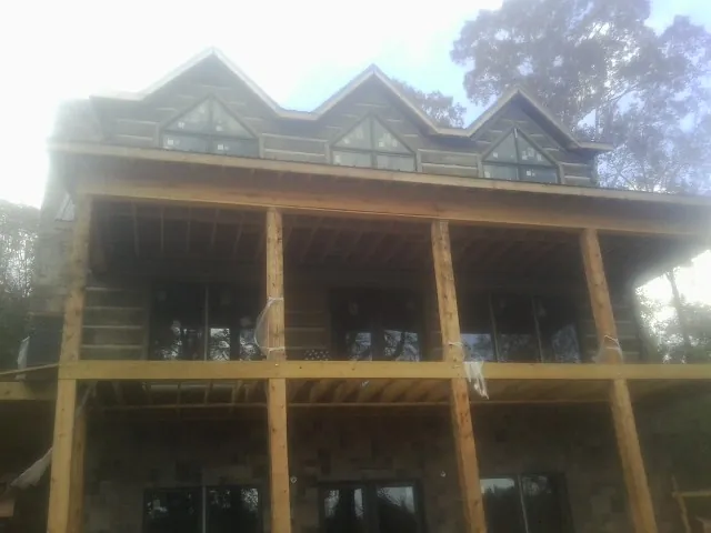 Dormers and porch framing on a large log home under construction — Roof Coating work by our crew in Twin Valley