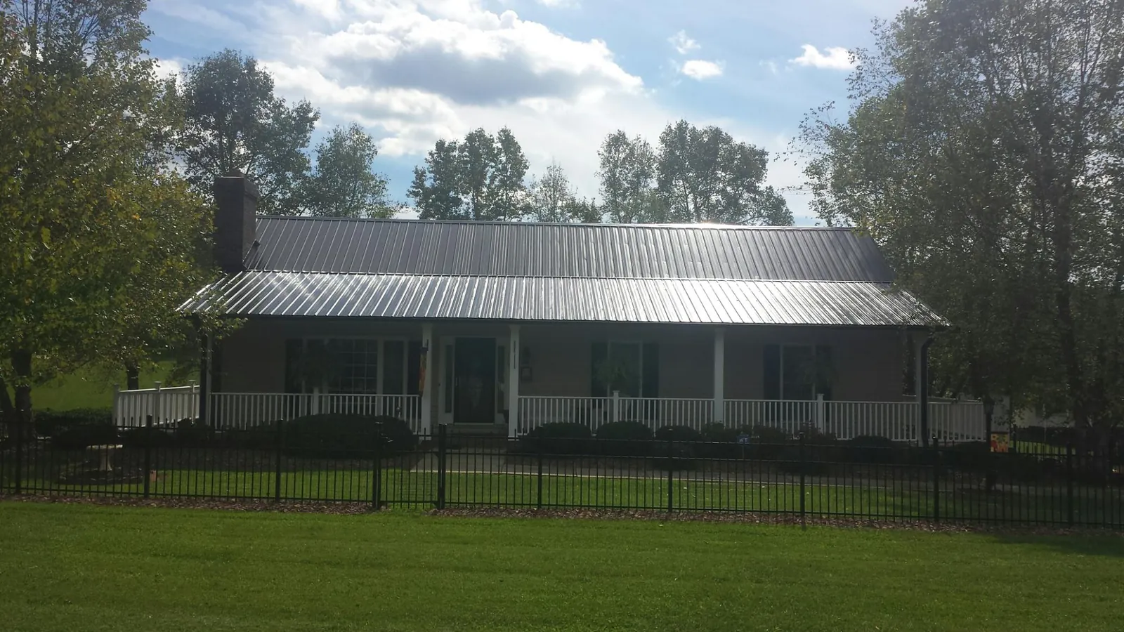 Gray metal roof on a brick ranch with a full width front porch — Gutter Guard Installation work by our crew in Twin Valley