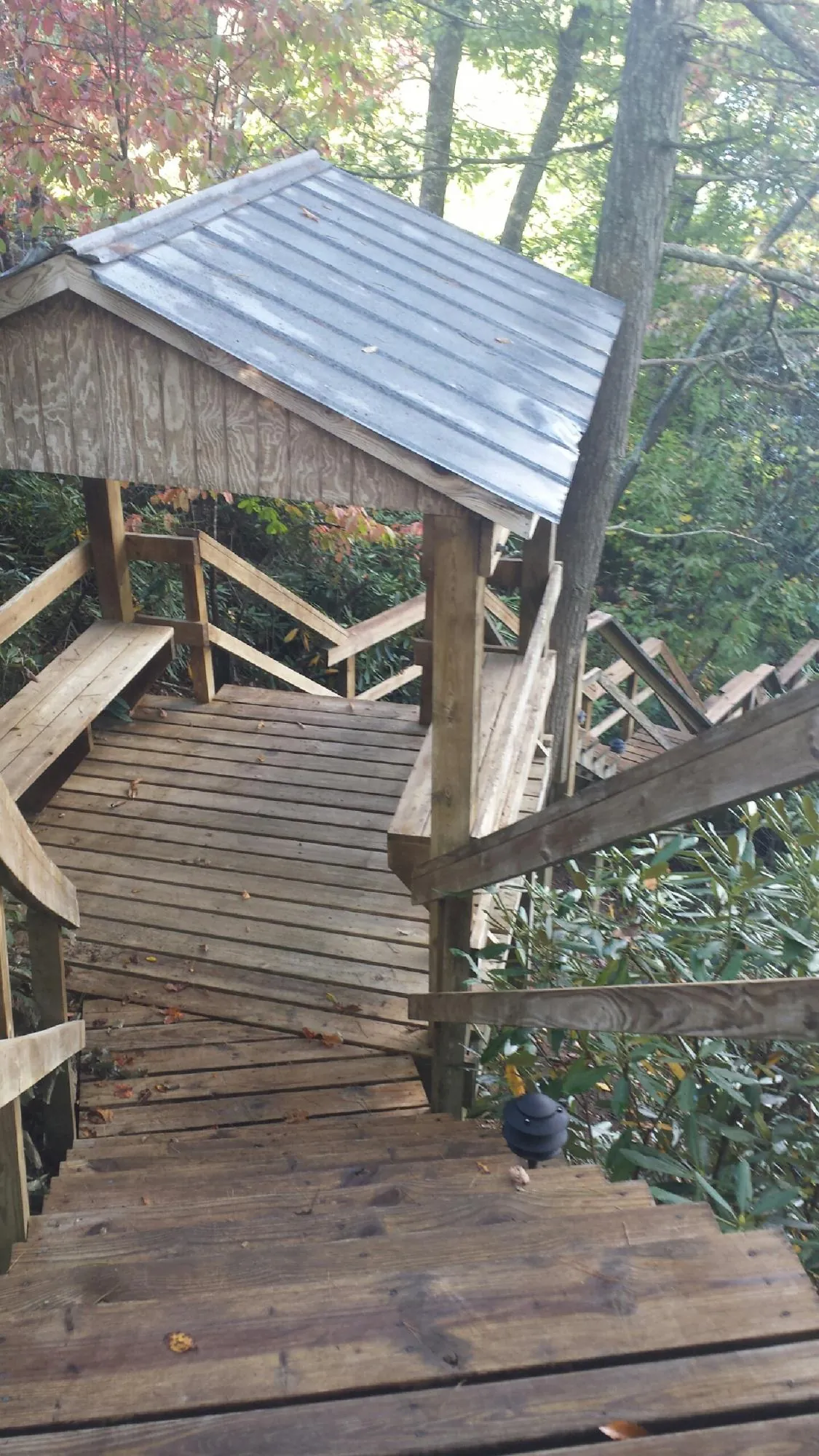 Metal roofed shelter over wooden steps on a wooded walkway — Skylight Repair & Installation work by our crew in Twin Valley
