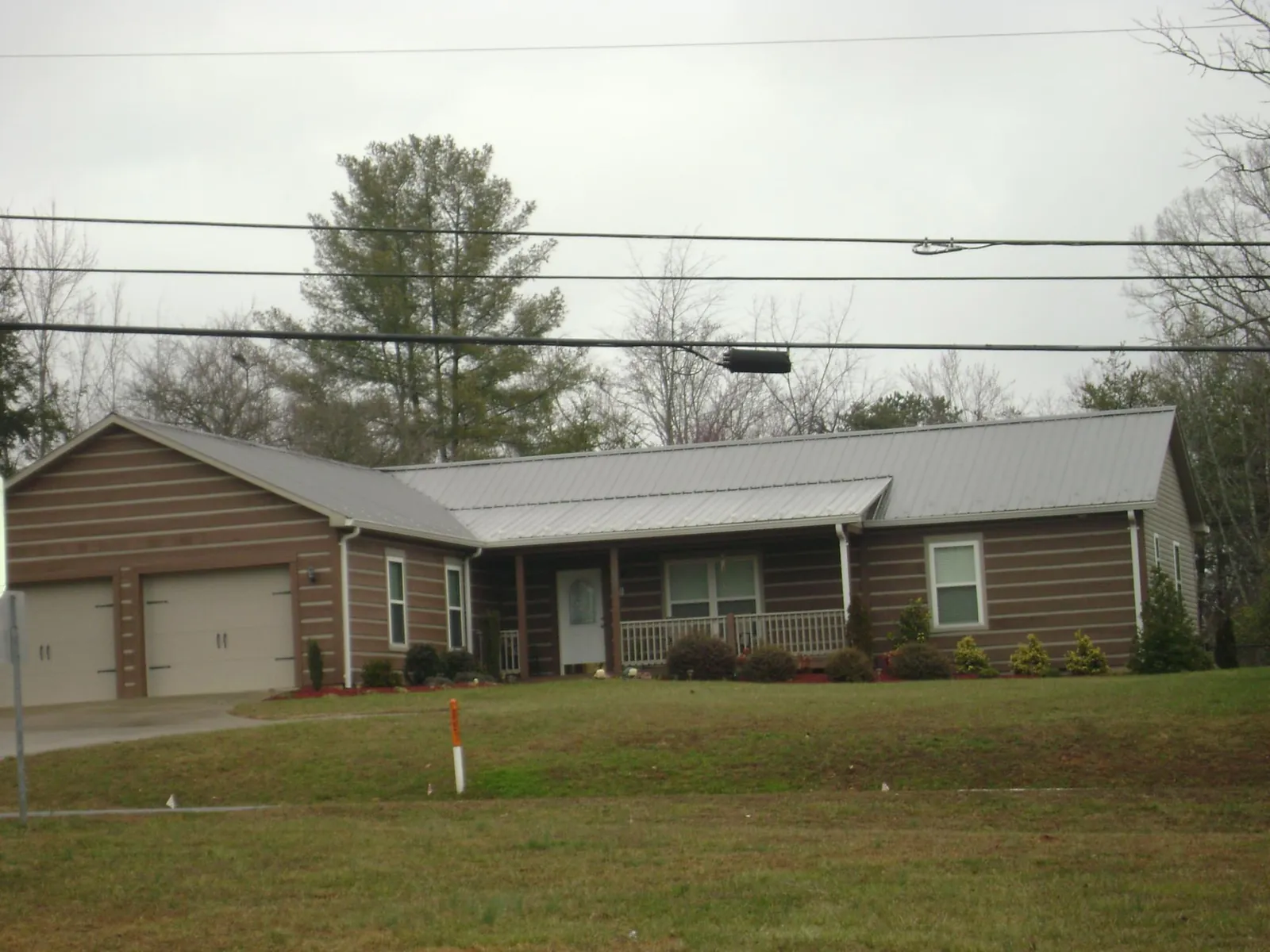 Gray metal roof on a log sided ranch home with a front porch in Twin Valley