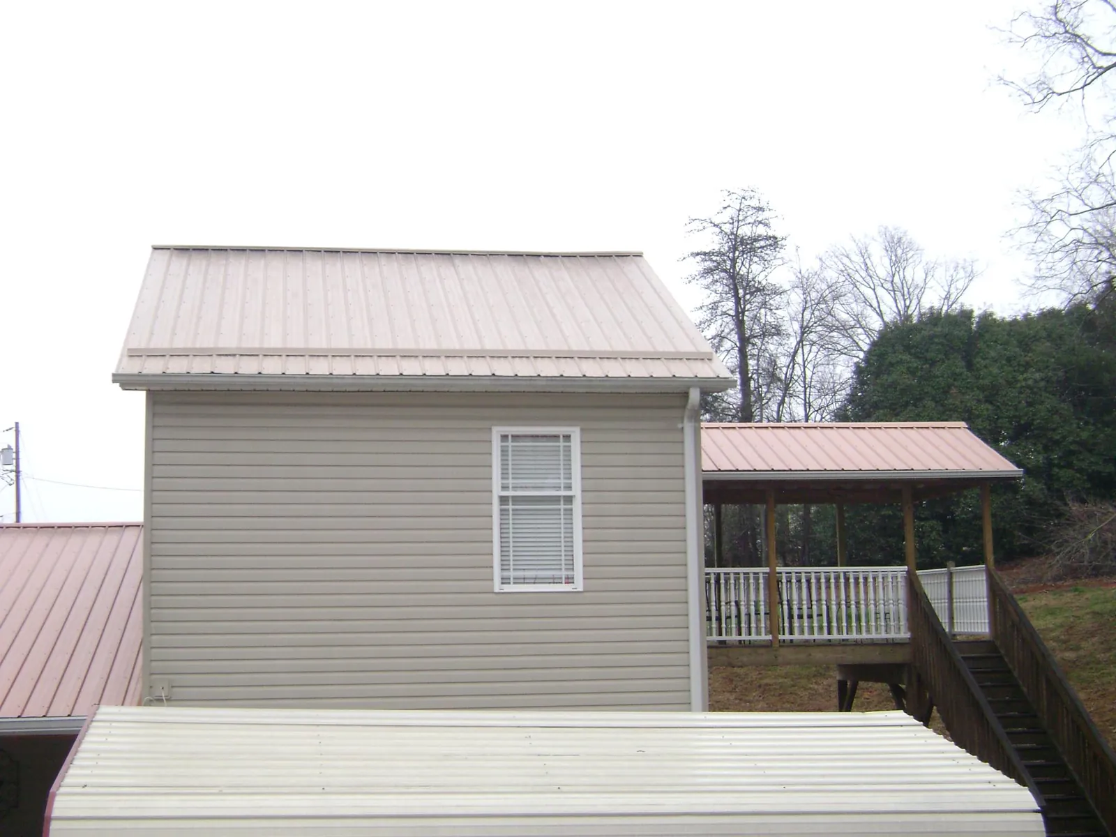 Tan metal roofs on a two story addition and attached porch, from a Roof Replacement job in Twin Valley