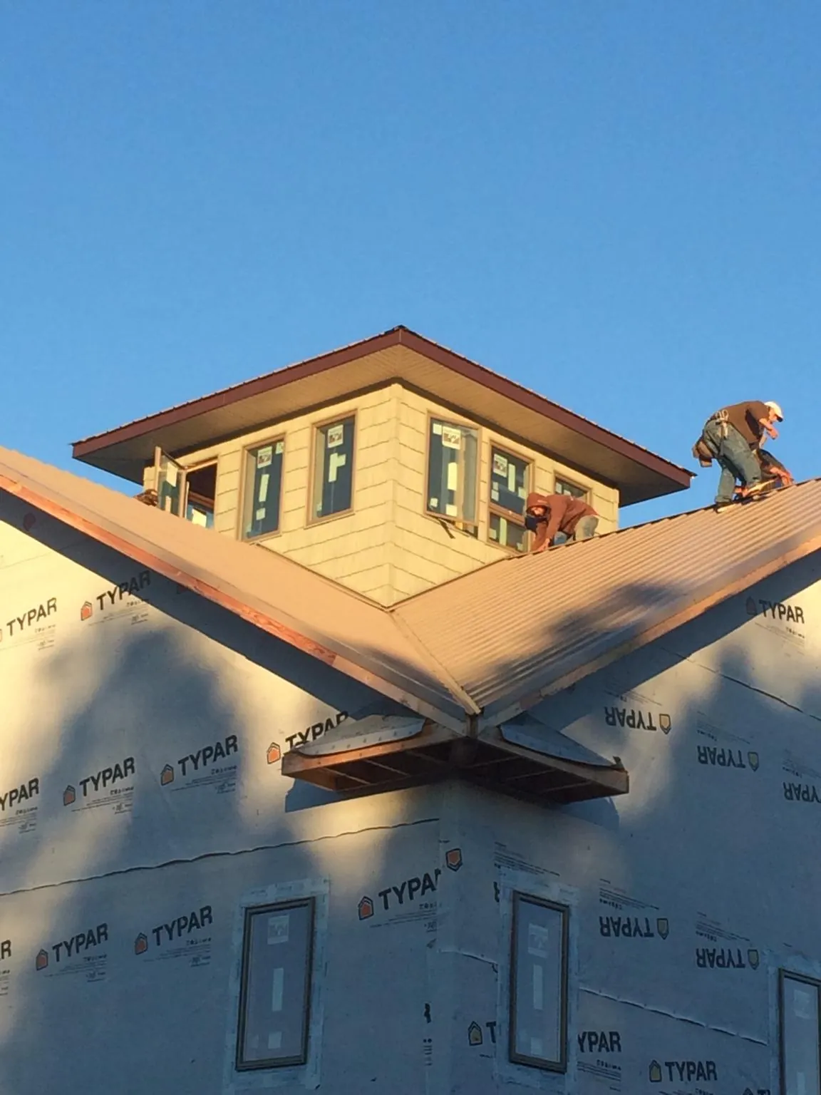 Roofers working around a rooftop cupola on a new metal roof at sunset — Roof Waterproofing in Twin Valley by Roofing Brothers